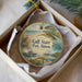 A decorative ornament in a box, featuring a beach scene with a bird, a turtle, and a pier.