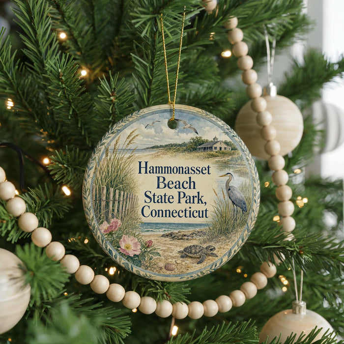 A round ornament hanging on a Christmas tree, featuring a scenic image of a beach and park with a bird in the foreground.