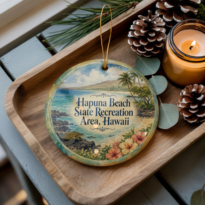 A decorative ornament with a tropical beach scene, featuring palm trees, flowers, and a seascape, is displayed on a wooden tray alongside pine cones and a lit candle.