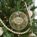 A Christmas tree decorated with ornaments, including a circular ornament with a scenic image of a park and a deer.