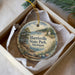 A decorative ornament in a box, featuring a scenic landscape with a lighthouse and trees, with the text "Harrisville State Park, Michigan" printed on it.