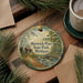 A decorative ornament featuring a scenic image of Hartwick Pines State Park in Michigan, surrounded by pine branches and a cup of coffee on a wooden surface.