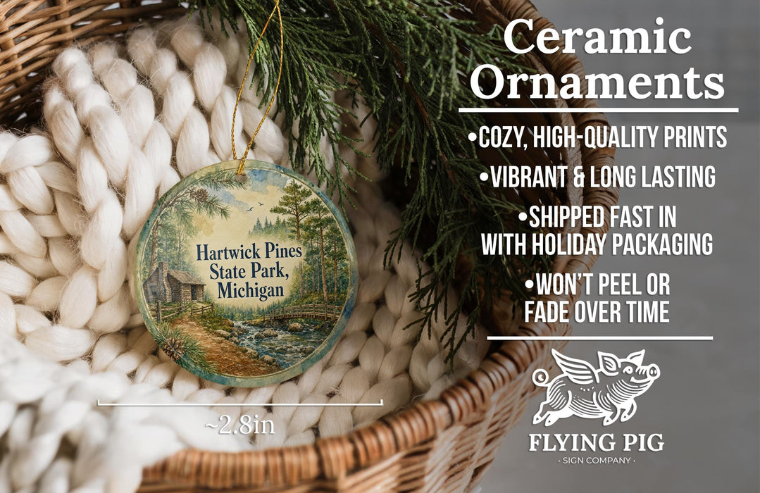 Ceramic ornaments, featuring a painting of a scenic view of Hartwick Pines State Park, Michigan, hanging from a wicker basket.