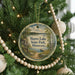 A round ornament hanging on a Christmas tree, featuring a scenic image of a lake and park.
