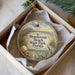 A round ornament with a beach scene and a bird is displayed in a box.