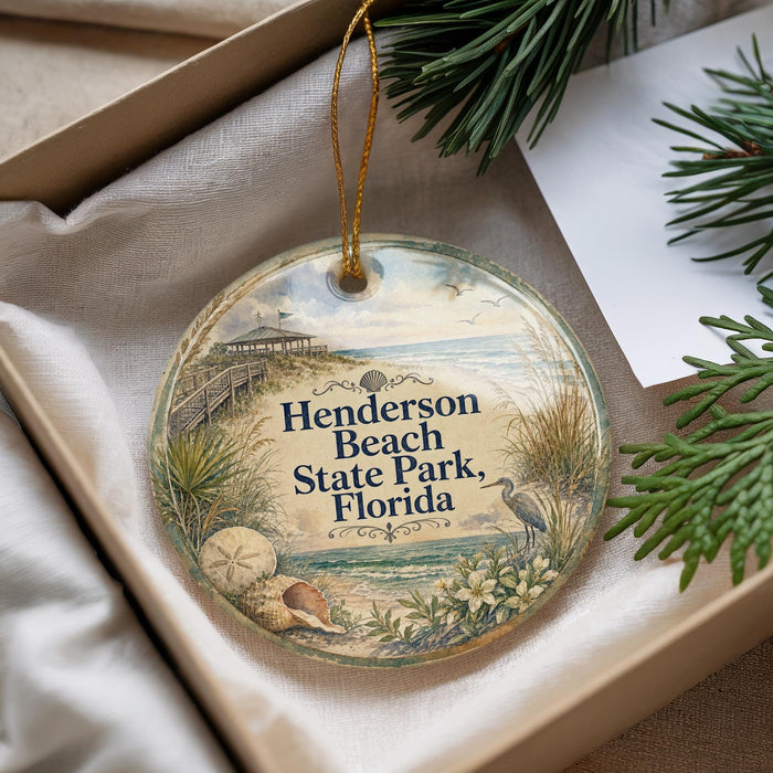 A round ornament with a beach scene and the text "Henderson Beach State Park, Florida" is displayed in a box with pine branches.