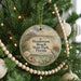 A round ornament hanging on a Christmas tree, featuring a beach scene with a pier and palm trees.