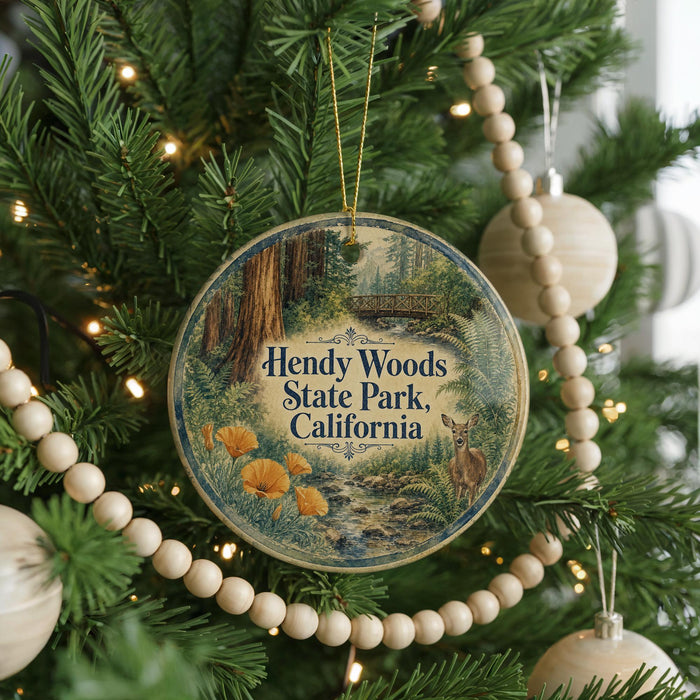 A round ornament hanging on a Christmas tree, featuring an illustration of Hendy Woods State Park, California.