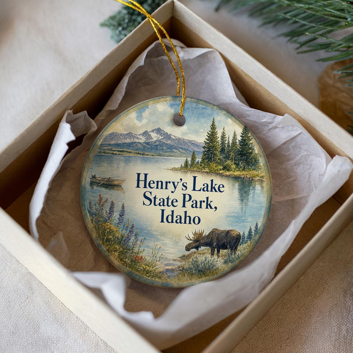 A round ornament with a scenic image of Henry's Lake State Park, Idaho, featuring a moose, a boat, and a mountain landscape.