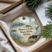 A decorative ornament with a moose and a scenic landscape, featuring mountains and a lake, is displayed in a box with pine branches.