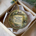A decorative ornament in a box, featuring a painting of a house and a bird, with the text "Herrington Manor State Park, Maryland" on it.