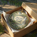A decorative ornament in a box, featuring a scenic image of High Falls State Park, Georgia.