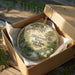 A decorative ornament in a wooden box, featuring a scenic image of Hillsborough River State Park in Florida.
