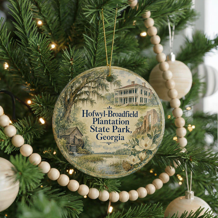 A round ornament hanging on a Christmas tree, featuring a scenic image of a plantation house surrounded by greenery.