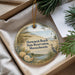 A decorative ornament in a box, featuring a beach scene with a lighthouse, seagull, and other natural elements.