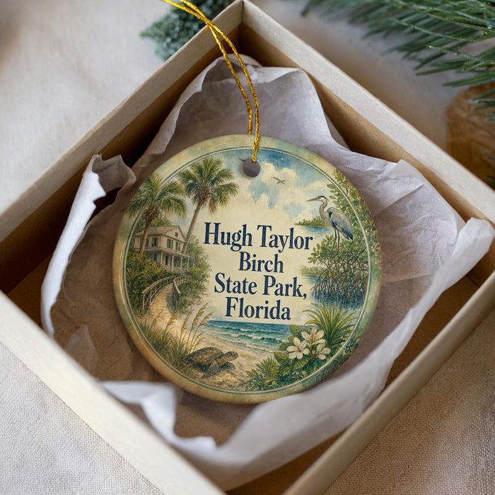 A round ornament with a tropical scene, including palm trees, a house, and a bird, is displayed in a white box.
