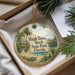 A decorative ornament with a tropical beach scene, featuring palm trees, a house, and a bird, is displayed in a box with pine branches.
