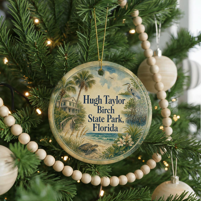 A round ornament hanging on a Christmas tree, featuring a tropical beach scene with palm trees, a house, and a bird.