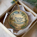 A decorative ornament in a box, featuring a lighthouse and a beach scene with flowers and a bird.