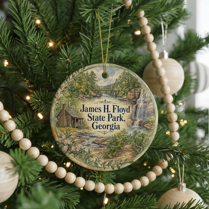 A round ornament hanging on a Christmas tree, featuring a scenic image of James H. Floyd State Park, Georgia.