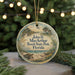 A round ornament with a beach scene and a bird, hanging on a string.