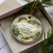A decorative ornament in a box, featuring an illustration of a building and palm trees, with the text "John Gorrie Museum State Park, Florida" printed on it.