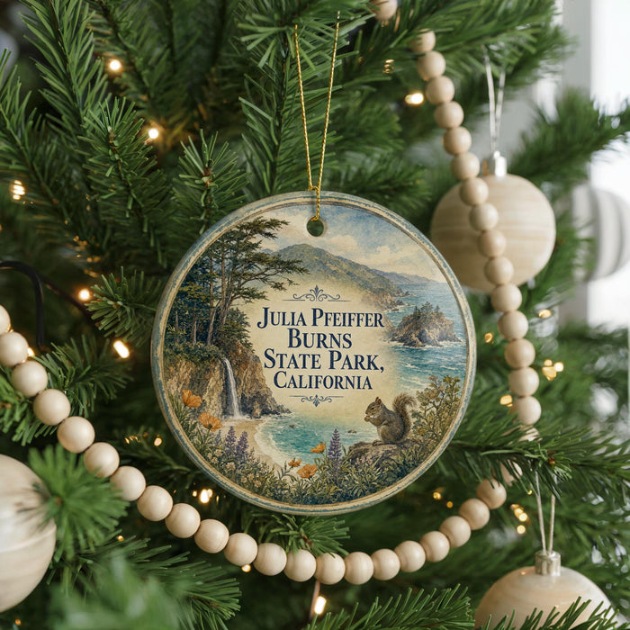 A round ornament hanging on a Christmas tree, featuring a scenic landscape with a waterfall and mountains.