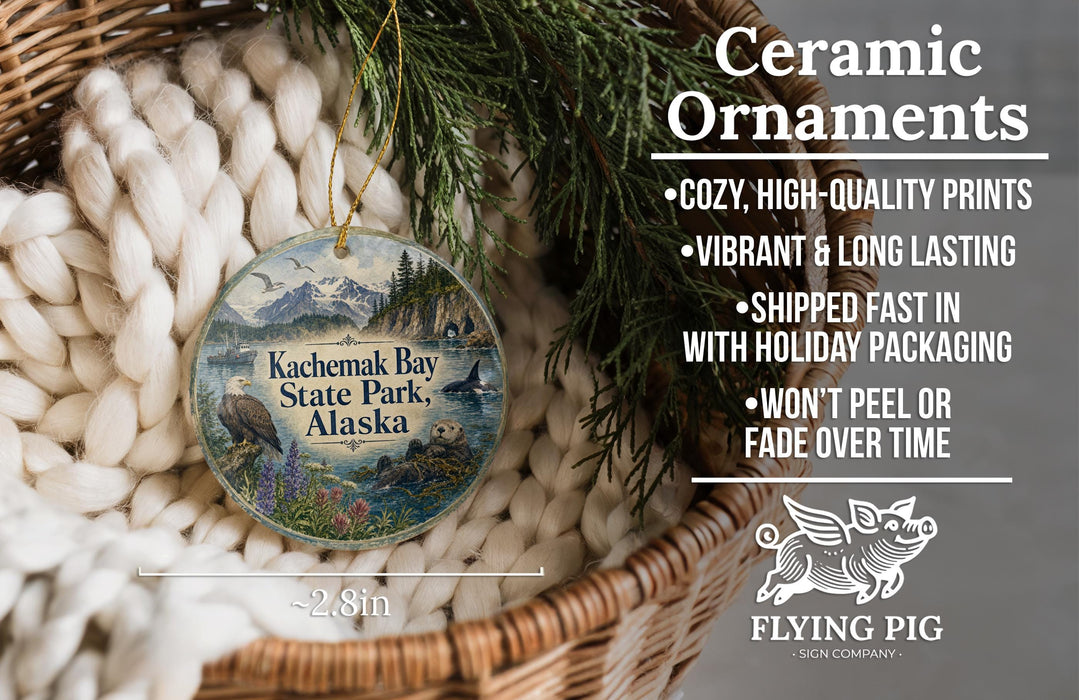 Ceramic ornaments, featuring a bird and a landscape, are displayed in a basket with pine branches.