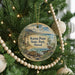 A round ornament hanging on a Christmas tree, featuring a lighthouse and a bird, with the text "Kaena Point State Park, Hawaii" displayed on it.