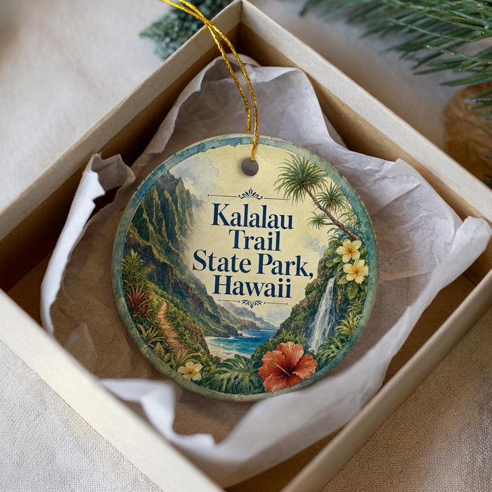 A circular ornament with a tropical landscape design, featuring palm trees, a waterfall, and a hibiscus flower, is displayed in a white box.
