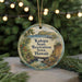 A circular ornament with a tropical landscape and text, hanging on a string.