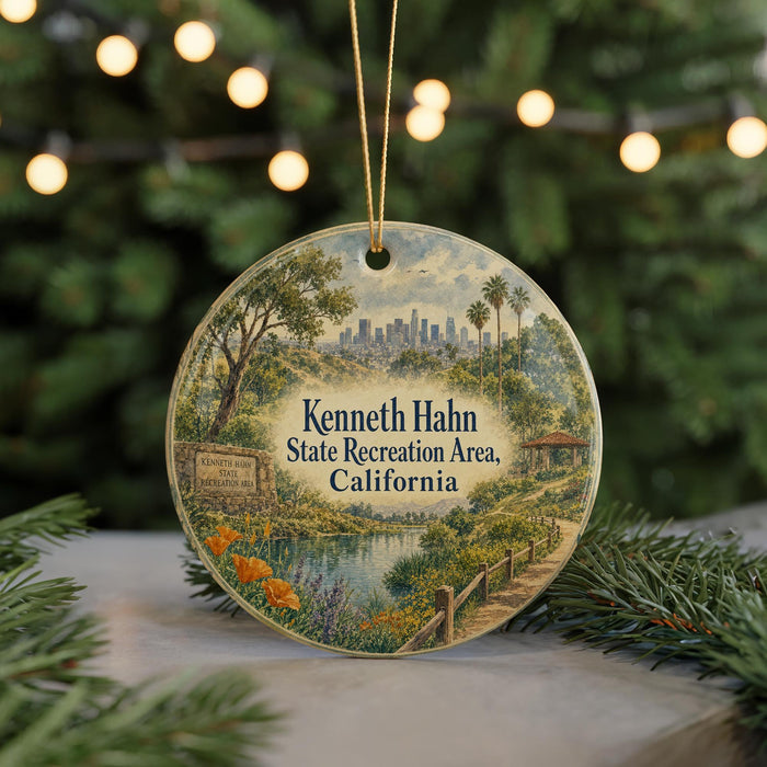 A circular ornament with a painting of a scenic landscape, featuring a city skyline in the background and a path leading to a body of water.