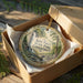 A decorative ornament in a box, featuring a scenic image of Kent Falls State Park in Connecticut.