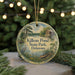 A round ornament with a painting of a pond and surrounding scenery, hanging from a string.