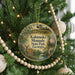 A round ornament hanging on a Christmas tree, featuring a deer and surrounded by greenery.