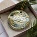 A decorative ornament with a scenic landscape of Lacquis Parle State Park, Minnesota, featuring a bird, water, and greenery.