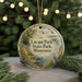 A circular ornament with a scenic landscape featuring a lake, trees, and birds, hanging from a string.