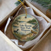 A decorative ornament in a box, featuring a scenic landscape with a lake, pine trees, and a bird, along with the text "Lake Bemidji State Park, Minnesota".