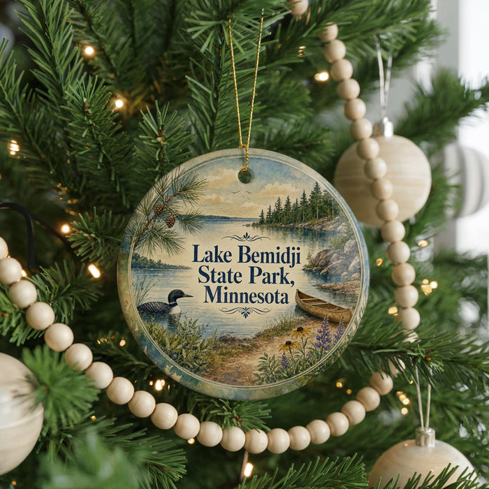 A round ornament hanging on a Christmas tree, featuring a scenic image of Lake Bemidji State Park in Minnesota.