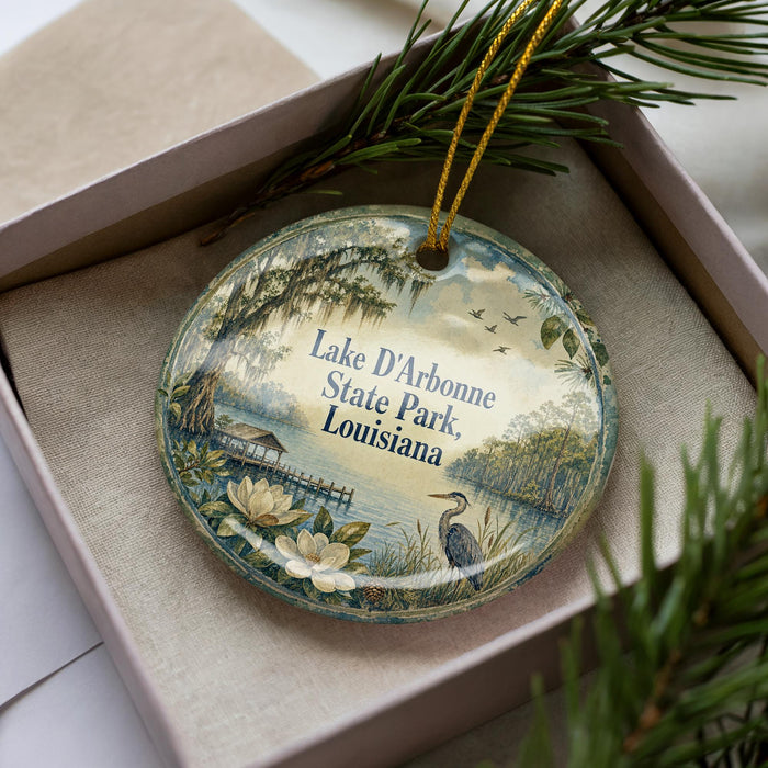 A decorative ornament with a lake, birds, and greenery, placed in a box with pine branches.