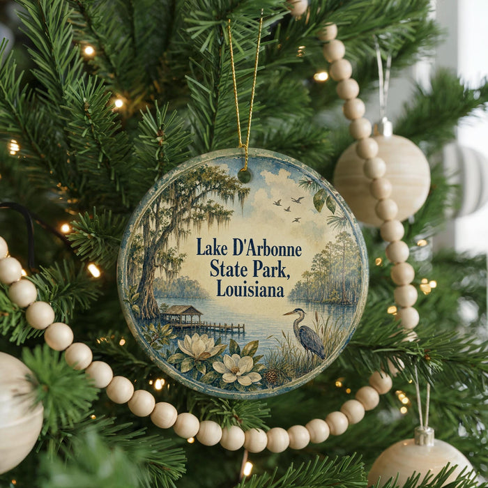 A round ornament hanging on a Christmas tree, featuring a scenic landscape with a lake, trees, and birds.