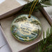 A decorative ornament in a box, featuring a scenic image of Lake Kissimmee, Florida, with a bird and palm trees in the background.