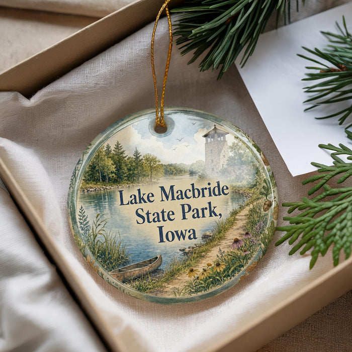 A decorative ornament with a scenic lake and park landscape, featuring a boat on the water and a tower in the background.