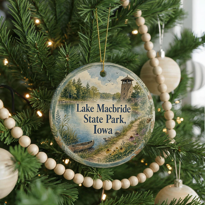 A round ornament hanging on a Christmas tree, featuring a scenic image of Lake Macbride State Park in Iowa.