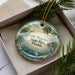 A decorative ornament in a box, featuring a scenic image of Lake Manatee State Park, Florida.