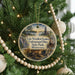 A circular ornament hanging on a Christmas tree, featuring a scenic image of Lake Vermilion Soudan, an underground mine, and a sunset over the water.