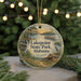 A circular ornament featuring a scenic landscape of Lakepoint State Park, Alabama, with a bird perched on a branch and a wooden cabin in the background.
