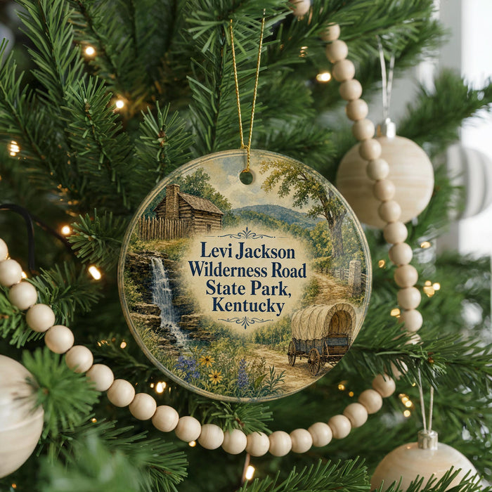 A round ornament hanging on a Christmas tree, featuring a scenic image of a cabin and a waterfall surrounded by greenery.