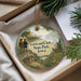 A decorative ornament with a scenic landscape featuring a cabin, a river, and two figures, along with text that reads "Lewis and Clark State Park, Iowa".