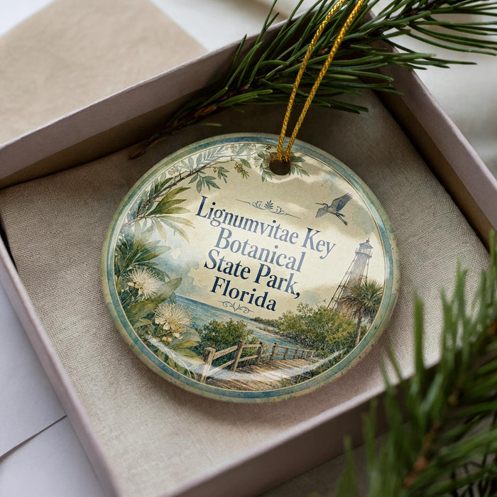 A round ornament with a floral design and text, placed in a box with pine branches.